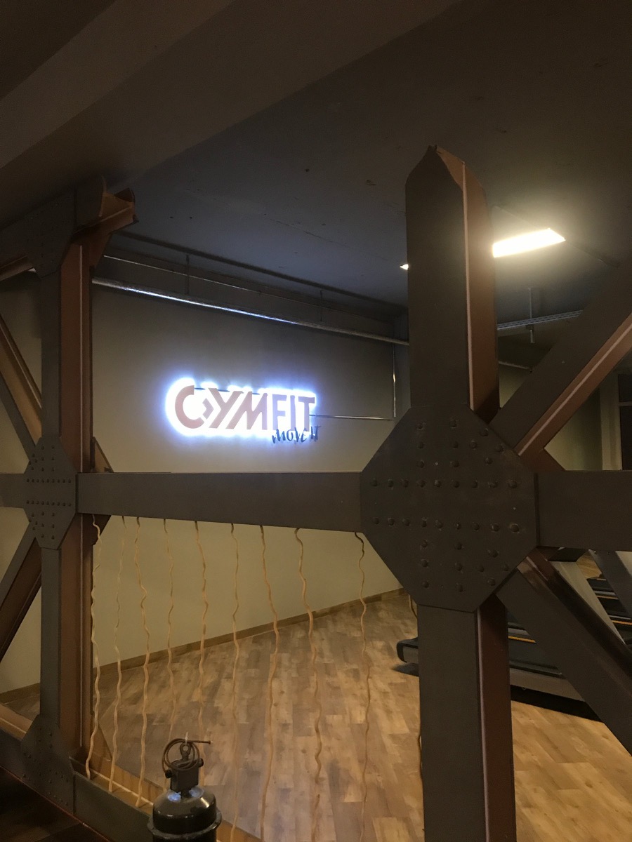 Wandelemente mit Nieten vor Ort, dahinter ein hinterleuchtetes Logo