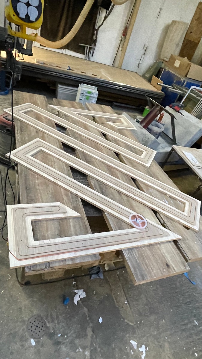 CNC-gefräste Logo-Teile aus Holz auf dem Werkstatttisch