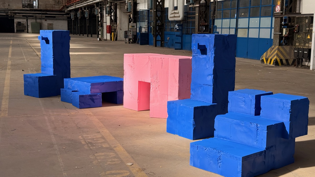 Blaue und rosa Sitz- und Podestelemente mit rauer Oberfläche in einer Werkhalle